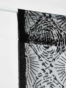 Detail of black lace halloween curtain featuring intricate floral weave and mesh texture