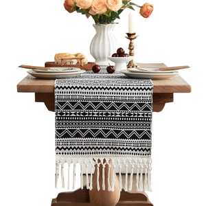 Bohemian black and white wave pattern table runner with tassels on a wooden dining table