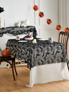 Detailed texture of black lace Halloween tablecloth featuring bat and spider web patterns