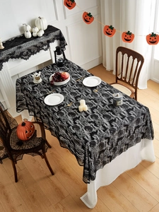 Detail of black lace Halloween tablecloth featuring intricate bat and spider web patterns