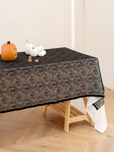 Dettaglio tovaglia di Halloween in pizzo nero con motivo a ragnatela su tessuto bianco