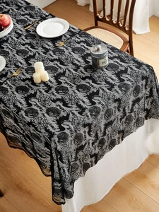 Intricate black lace tablecloth detail with spider webs and bats for Halloween decor
