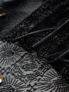 Dettaglio della tovaglia in pizzo nero con intricati motivi a ragnatela e geometrici