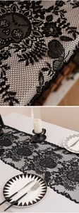 Close-up of black lace Halloween table runner with intricate skull and floral cutout patterns
