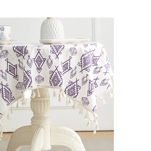 Detail of round white tablecloth with purple geometric patterns and elegant beige tassels