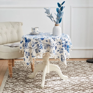 Detail einer runden Baumwoll-Leinen-Tischdecke mit blauem Blumendruck und Fransen