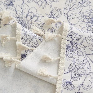 Macro detail of cotton linen tablecloth showing vintage floral patterns and fringe tassels