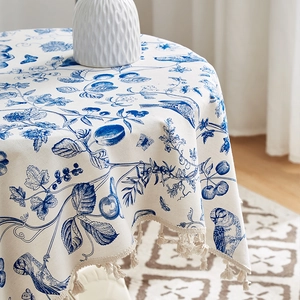 Detail einer runden Tischdecke aus Baumwollleinen mit blauen Pflanzenmotiven und kleinen Quasten