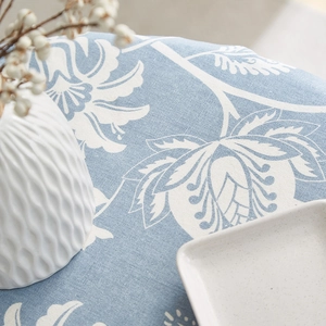 Close-up of blue cotton linen tablecloth with white floral pattern and ceramic decor