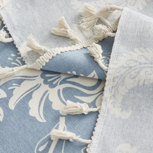 Close-up of light blue floral cotton linen tablecloth with elegant white tassels