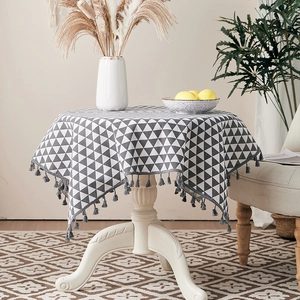 Detailed close-up of cotton linen tablecloth with grey triangles and tassel edge