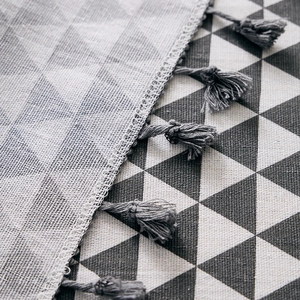 Close-up of geometric triangle pattern fabric with handmade grey fringe tassel edge