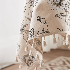 Macro shot of ink floral pattern on cotton linen tablecloth with elegant fringe tassels