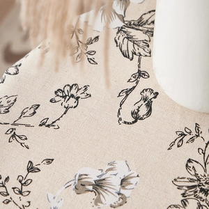 Macro shot of ink-wash style flower print on textured beige linen tablecloth fabric