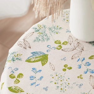 Linen table cloth with green leaf pattern on a dining table with a ceramic vase