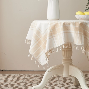 Detail of coffee plaid cotton linen tablecloth with elegant cream tassels and fringe