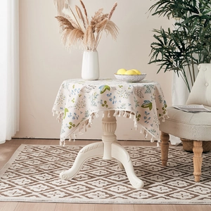 Detailed close-up of a floral cotton linen tablecloth with elegant fringe tassels on the edge