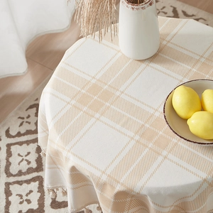 Brown checkered cotton linen round tablecloth with fringe tassels in a cozy home setting