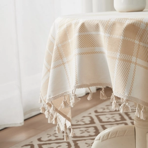 Detail of checkered brown cotton linen tablecloth with elegant fringe trim on a round table