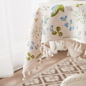 Detail of leaf print cotton linen tablecloth with ivory fringe and textured fabric