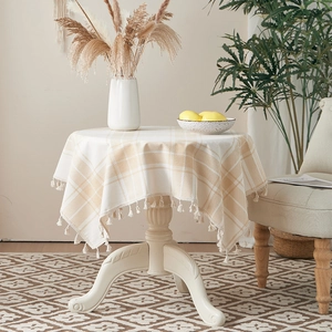 Close-up of brown checkered cotton linen tablecloth with decorative tassel fringe edges