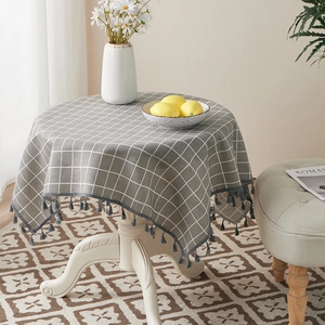 Close-up of grey and white checkered linen tablecloth with decorative tassel edges