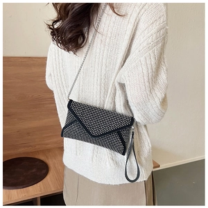 Détail d'une pochette noire à strass avec chaîne argentée et dragonne sur un mannequin