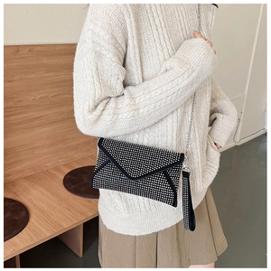 Détail de la pochette enveloppe noire ornée de strass brillants et bandoulière chaîne