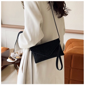 Vue détaillée du sac enveloppe noir à strass avec bandoulière chaîne sur un mannequin