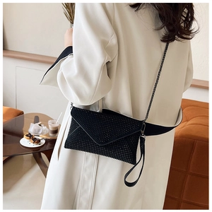Détail d'une pochette enveloppe noire à strass avec bandoulière sur un mannequin