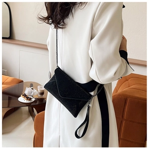 Vue arrière du mannequin portant une pochette enveloppe noire à strass avec chaîne