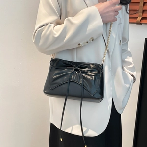 Black PU leather square bag with large bow and gold chain strap worn by a model