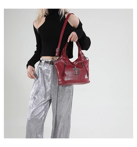 Detail of burgundy leather tote bag with vintage metal cross and adjustable strap on model