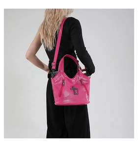 Detailed view of rose pink tote bag with black cross emblem and metallic zippers