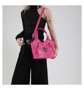 Hot pink glossy leather crossbody bag with silver cross charm and chain detail on model