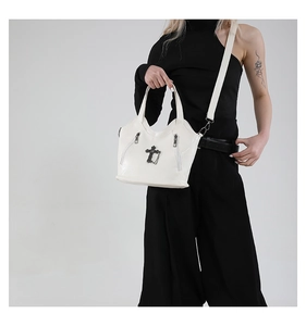 Cross-decorated retro white leather tote bag shown on model in a minimalist setting