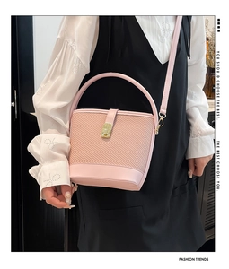 Detail of pink woven bucket bag featuring gold twist lock and leather shoulder strap