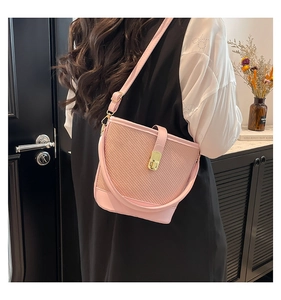 Pink woven bucket bag featuring gold metal turn-lock and adjustable leather shoulder strap