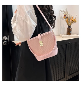 Detail of light pink woven bucket bag with smooth leather trim and golden twist-lock closure