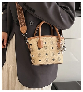 Modèle portant le sac seau beige à motif ours et bandoulière tissée avec logo