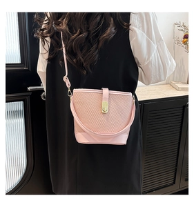 Detail of pink woven bucket bag featuring elegant metal twist lock and leather trim