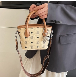 Détail du sac seau beige avec motif d'ours, cuir texturé et large bandoulière tissée