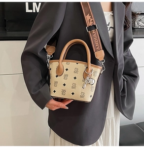 Vue détaillée du sac seau monogramme avec motif ours, bandoulière et pendentif ours