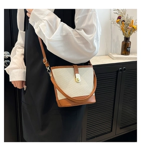 Détail d'un sac seau tissé avec bordure en cuir marron et fermoir rotatif doré
