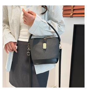 Close-up of black woven bucket bag featuring gold rectangular buckle and handle detail