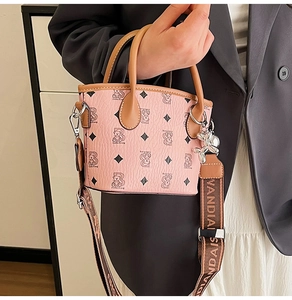 Détails d'un sac seau rose avec imprimé ours, bandoulière large et breloque chien