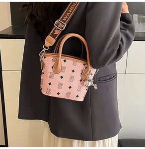 Sac seau rose en cuir avec motif d'ours et bandoulière logo porté par un mannequin