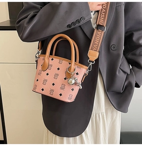 Détail du sac seau rose avec motif d'ours et large bandoulière en toile tissée