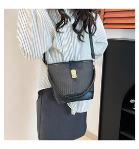 Détail du sac seau en cuir noir texturé avec fermoir doré rotatif et fine bandoulière en cuir