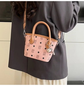 Sac seau rose avec motif monogramme d'ours, porté en bandoulière par un mannequin